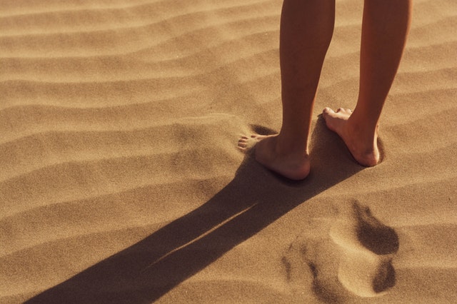 Osoba s bosými nohami stojaca v piesku.jpg